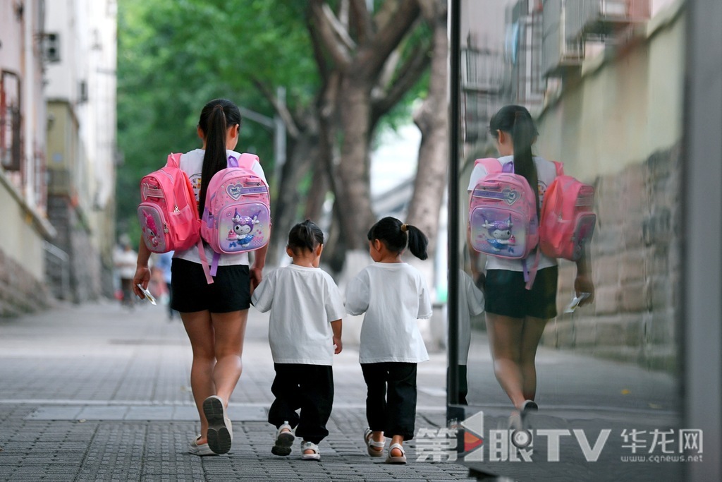 家长带着两个小朋友走在上学的路上。第1眼TV-华龙网记者 李一鸣 摄